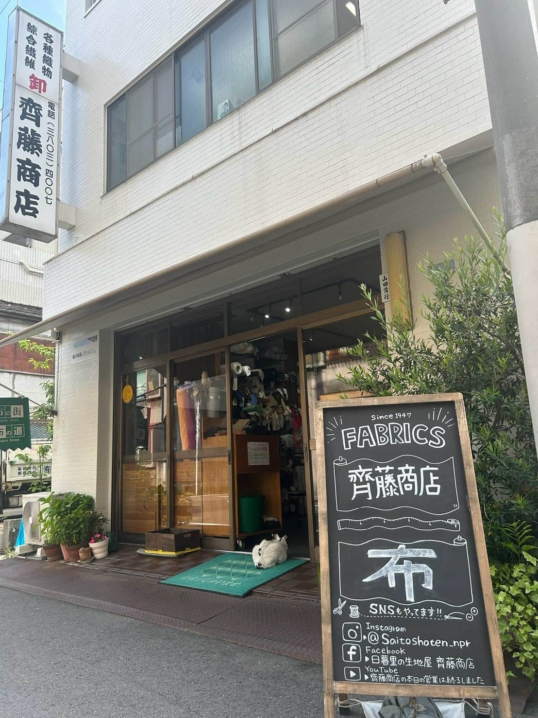日暮里繊維街にある生地店・齊藤商店の外観。入口に「FABRICS 齊藤商店」の黒板看板が立っている