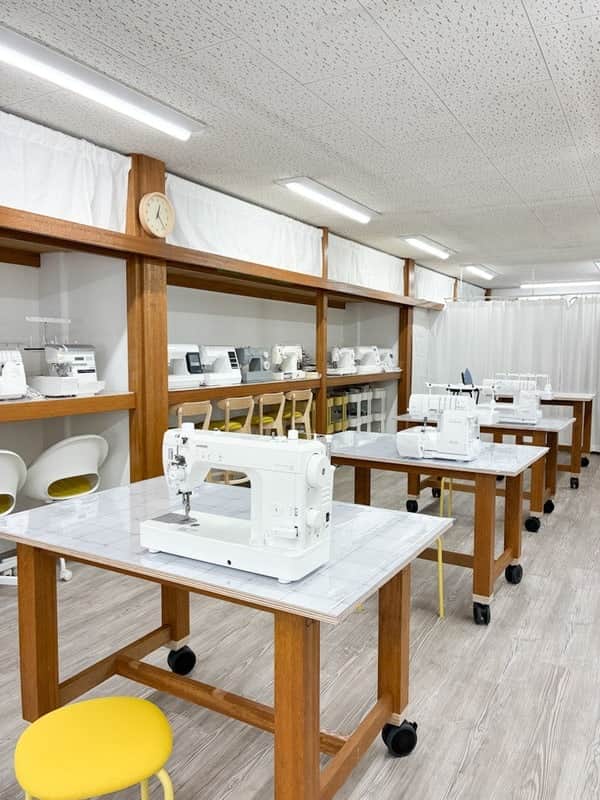 職業用ミシンを置いた作業台と黄色いスツールが並ぶ店内